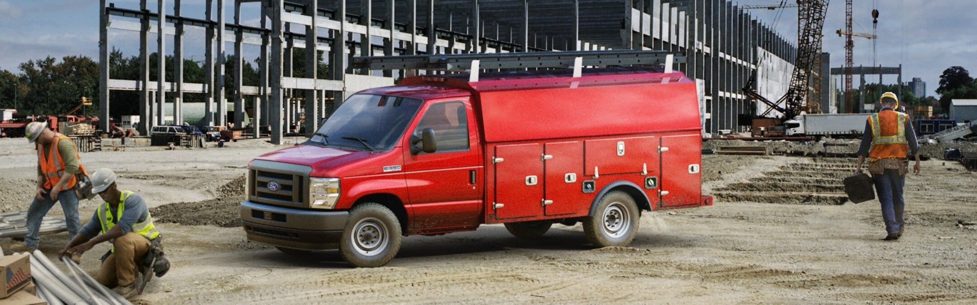 Red Ford utility service truck with ladder rack at a construction site with workers.