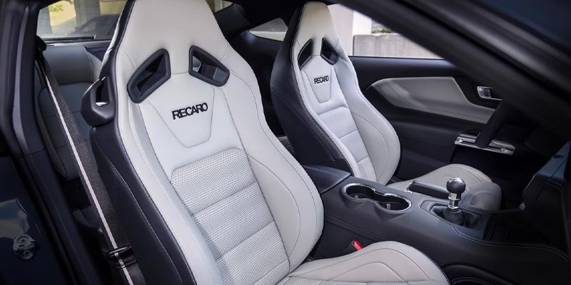 Interior view of a car with two-tone white and black Recaro sport seats, manual shifter, and center console.