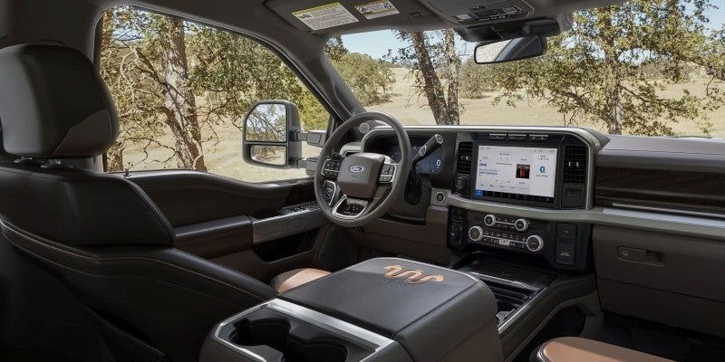 Luxury Ford truck interior with brown leather seats, a large touchscreen, and steering wheel, viewed from the passenger side.