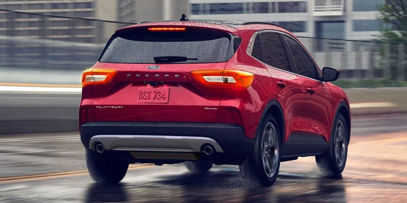 Red Ford Escape SUV driving away on a wet road in the rain with motion blur.