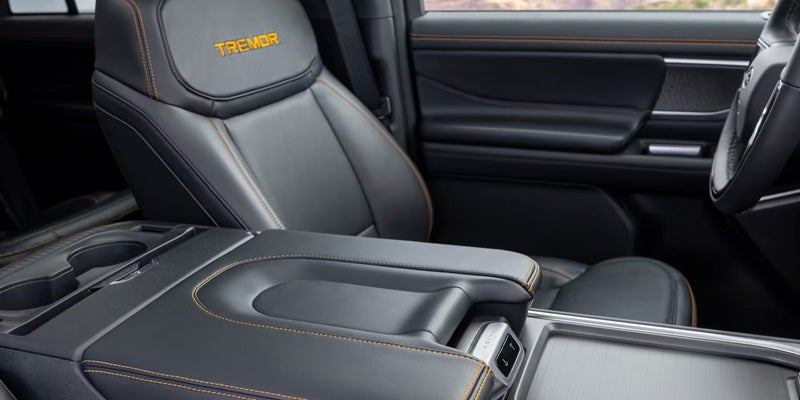 Black leather car interior with orange stitching, "TREMOR" logo on seat, and center console.
