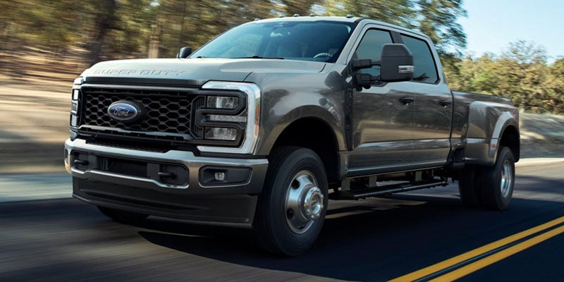 Gray Ford Super Duty dually pickup truck driving on a road.