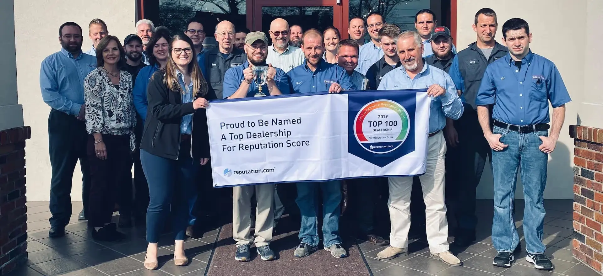 A group of employees holding a banner proclaiming their dealership as a 2019 Top 100 for
reputation score.