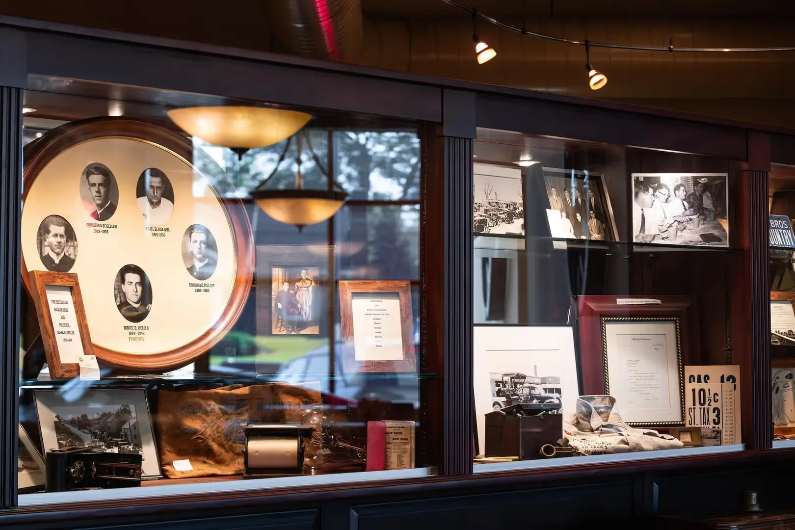 A glass display case showcasing historical photos, documents, and artifacts, including a large circular plaque with family portraits.