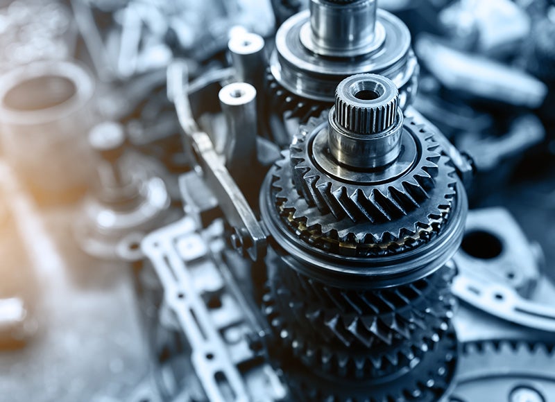 Close-up of shiny metal gears and shafts inside a mechanical assembly, likely a transmission.